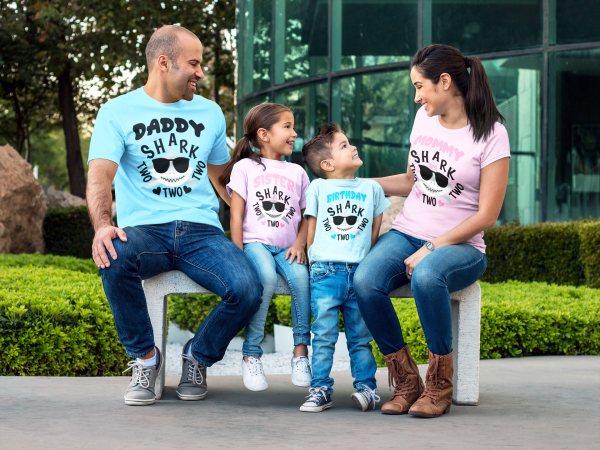 couple-with-kids-wearing-different-tees-mockup-sitting-on-a-bench-while-outdoors-a15484